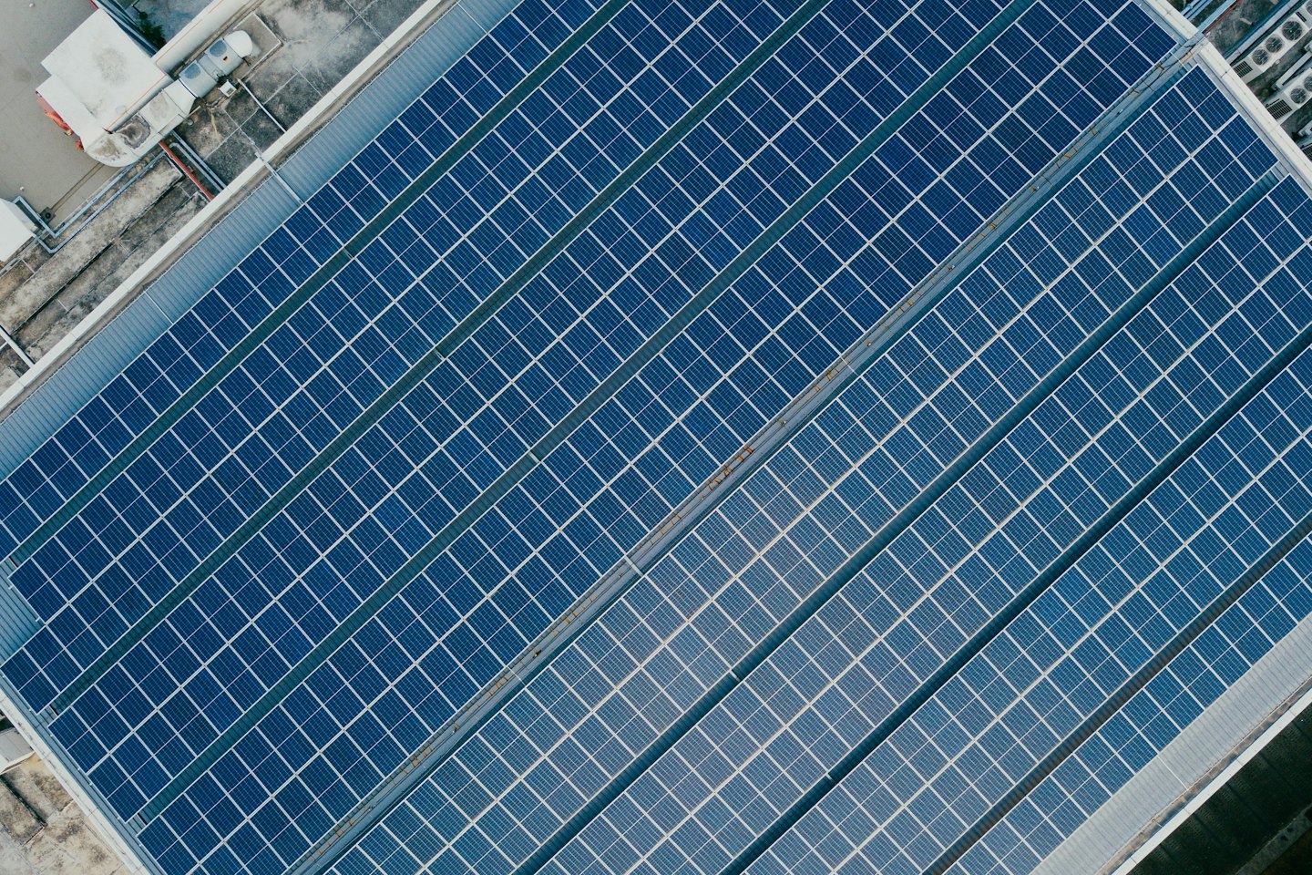 Blue solar panels covering a large commercial building rooftop.
